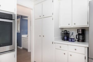 A kitchen with white cabinets, a coffee maker, and a Keurig coffee pod station. - Spacious 4-Bedroom Beach House with Pool and Ocean Views (Isle Of Palms)
