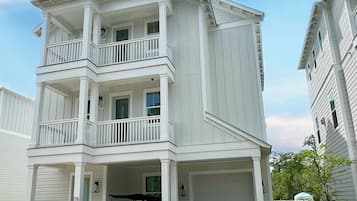 A two-story building with a covered front porch, a garage, and a driveway.