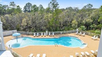 A pool area with lounge chairs and a view of a forested landscape.