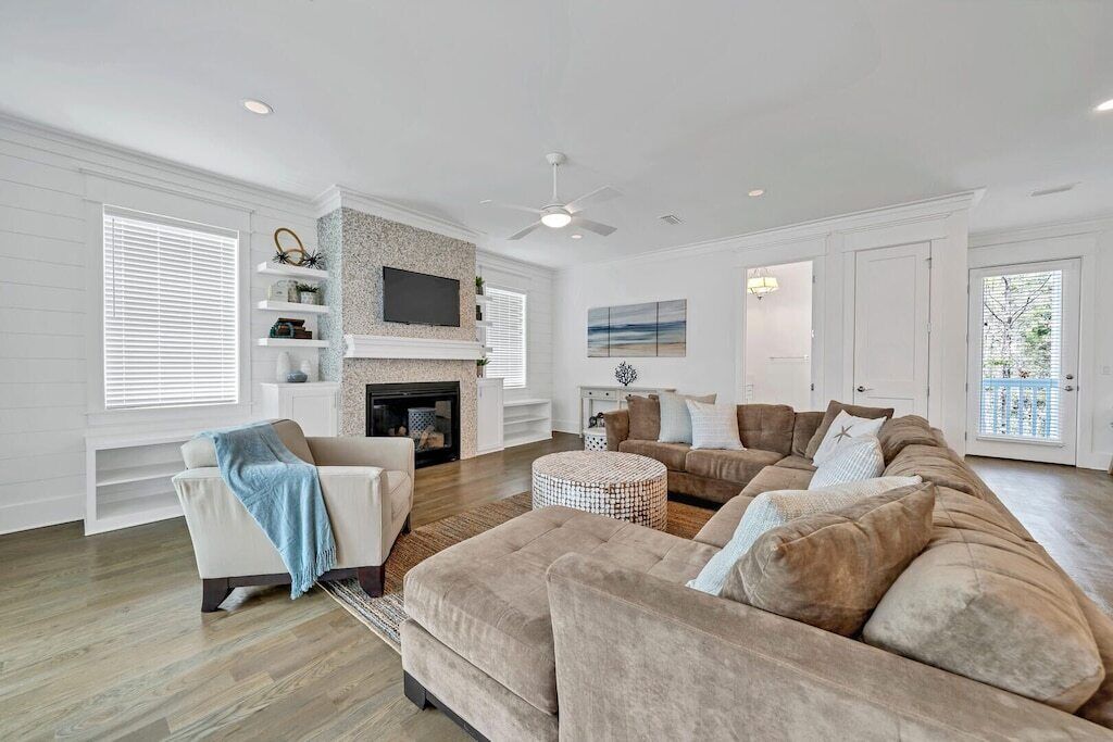 A spacious living room with a fireplace, a large sectional sofa, and a television mounted on the wall.