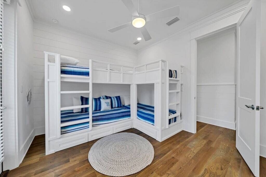A room with bunk beds, a ceiling fan, and a round rug.