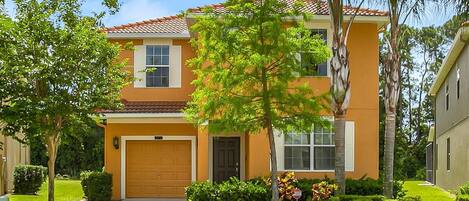 A two-story house with a red-tiled roof, a front garage, and a well-maintained lawn.