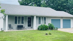 A single-story house with a front porch, two garage doors, and a small lawn area. -  Home on Quiet Cul de Sac with Handicap Accessibility (Kearney)