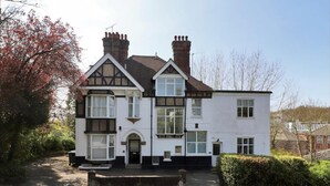A two-story house with a traditional design, featuring a prominent chimney, multiple windows, and a front entrance. - Beautiful 2-bed Apartment in Tunbridge Wells (Royal Tunbridge Wells)