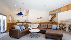 A spacious living room with a large sectional sofa, a round coffee table, and a fireplace. - Private 5-Acre Estate | Fishing Pond + Fire Pit (West Olive)