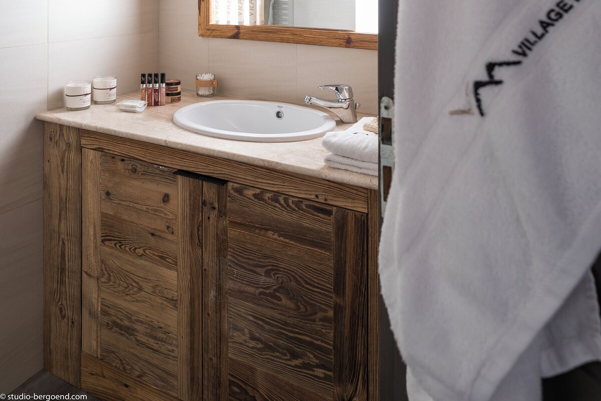 Un baño con tocador de madera, un espejo grande y un lavabo blanco.