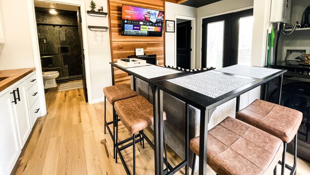 Une cuisine moderne dotée d’un îlot central, de tabourets de bar et d’un téléviseur à écran plat fixé au mur.