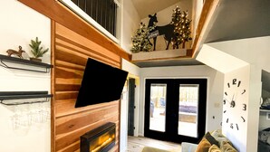 Un salon avec une cheminée, des boiseries, un canapé et un sapin de Noël.