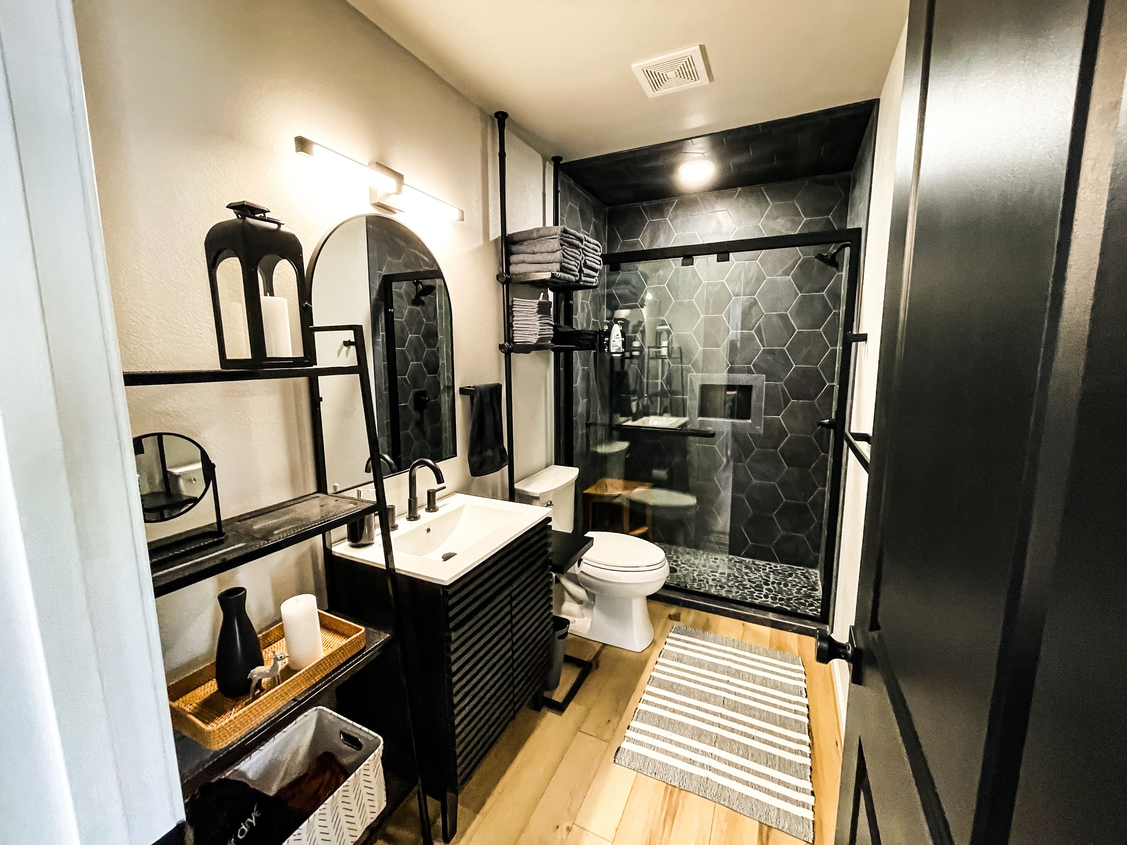 Une salle de bain moderne avec un lavabo noir, des toilettes blanches et une douche à parois de verre.