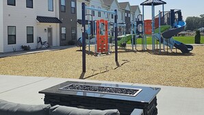 A playground with slides and climbing structures, surrounded by residential buildings.