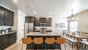 A modern kitchen with dark wood cabinets, stainless steel appliances, and a central island with bar stools.