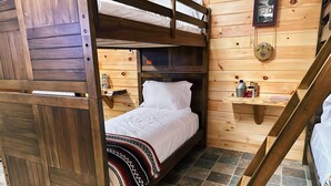 A bunk bed room with a wooden headboard, a bedside table with a lantern, and a shelf with a beer mug. - Cozy Lodge (Sherman)