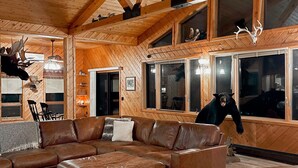 A spacious living room with a large L-shaped sectional sofa, wooden ceiling beams, and a ceiling fan. - Cozy Lodge (Sherman)