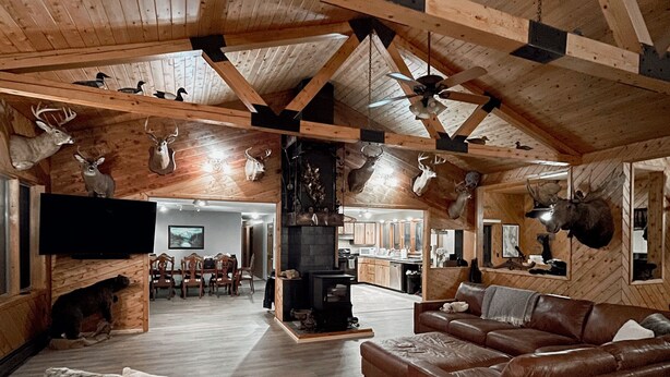 A spacious living area with a high ceiling, wooden beams, and a fireplace. There are leather sofas and a television. - Cozy Lodge (Sherman)