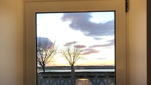 A room with a large window, a table with a lamp, and a vase with flowers. - Exceptional seafront location (Étel)