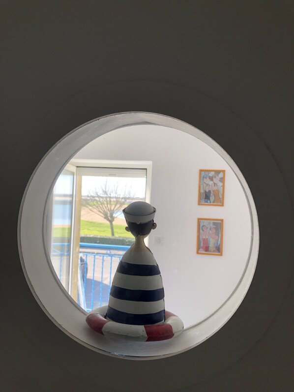 A circular window with a nautical-themed figurine inside.