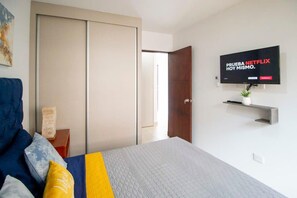 Ein Schlafzimmer mit einem Bett, einem an der Wand befestigten Fernseher und einem Schiebetürenschrank.