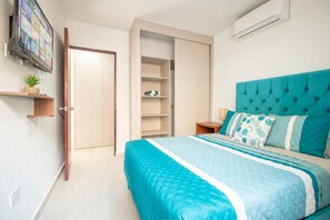 A bedroom with a bed, a wardrobe, a TV, and a shelf with a plant. - Stylish condo in Mazatlan l Pool & Terrace (Mazatlán)
