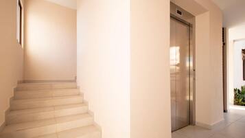 Ein helles, modernes Interieur mit einer Treppe, die zu einem Aufzug führt.