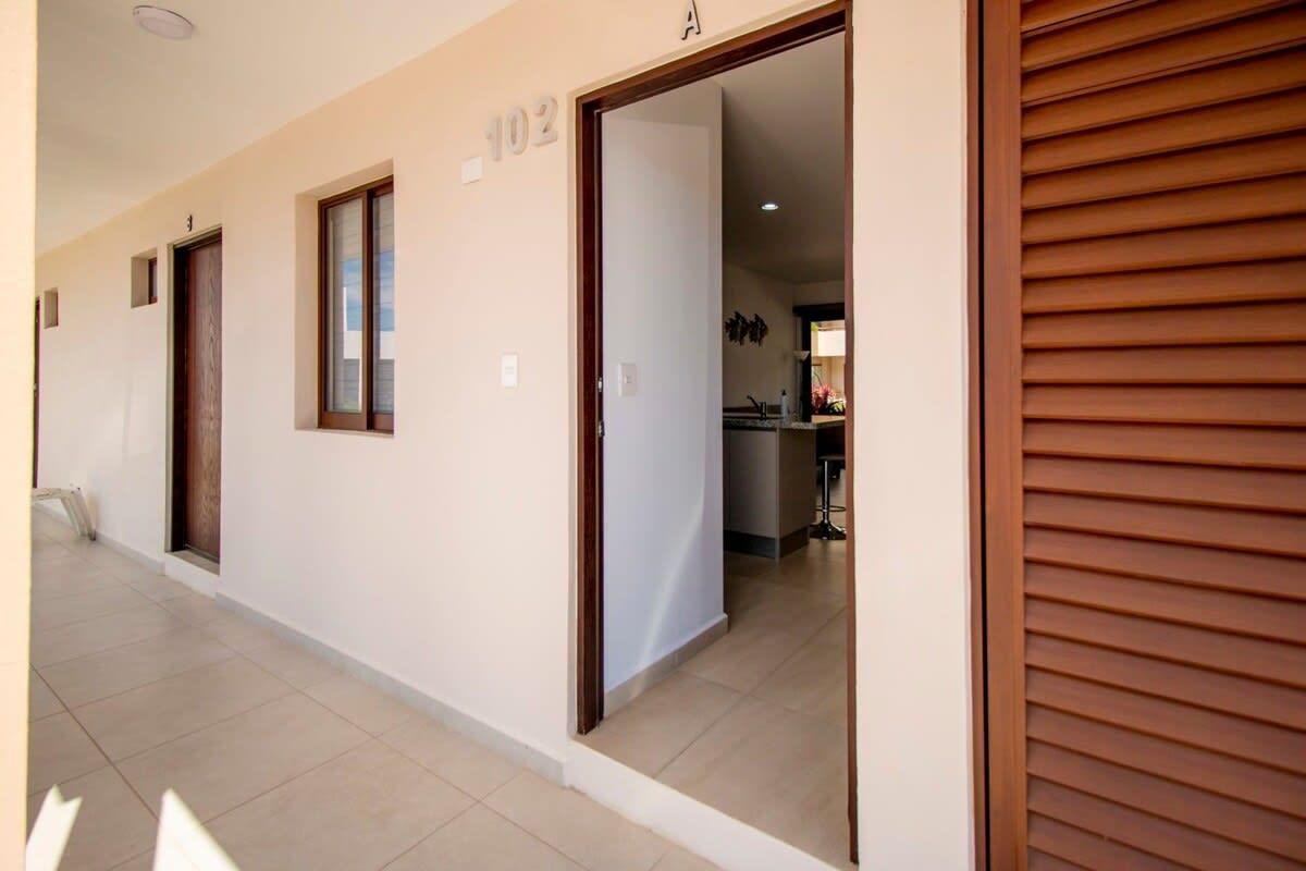 A corridor with doors numbered 102 and 103, leading to a room with a wooden shutter.