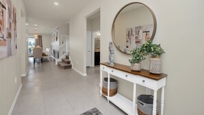 Een hal met een witte console tafel, een spiegel en een trap naar een andere kamer.