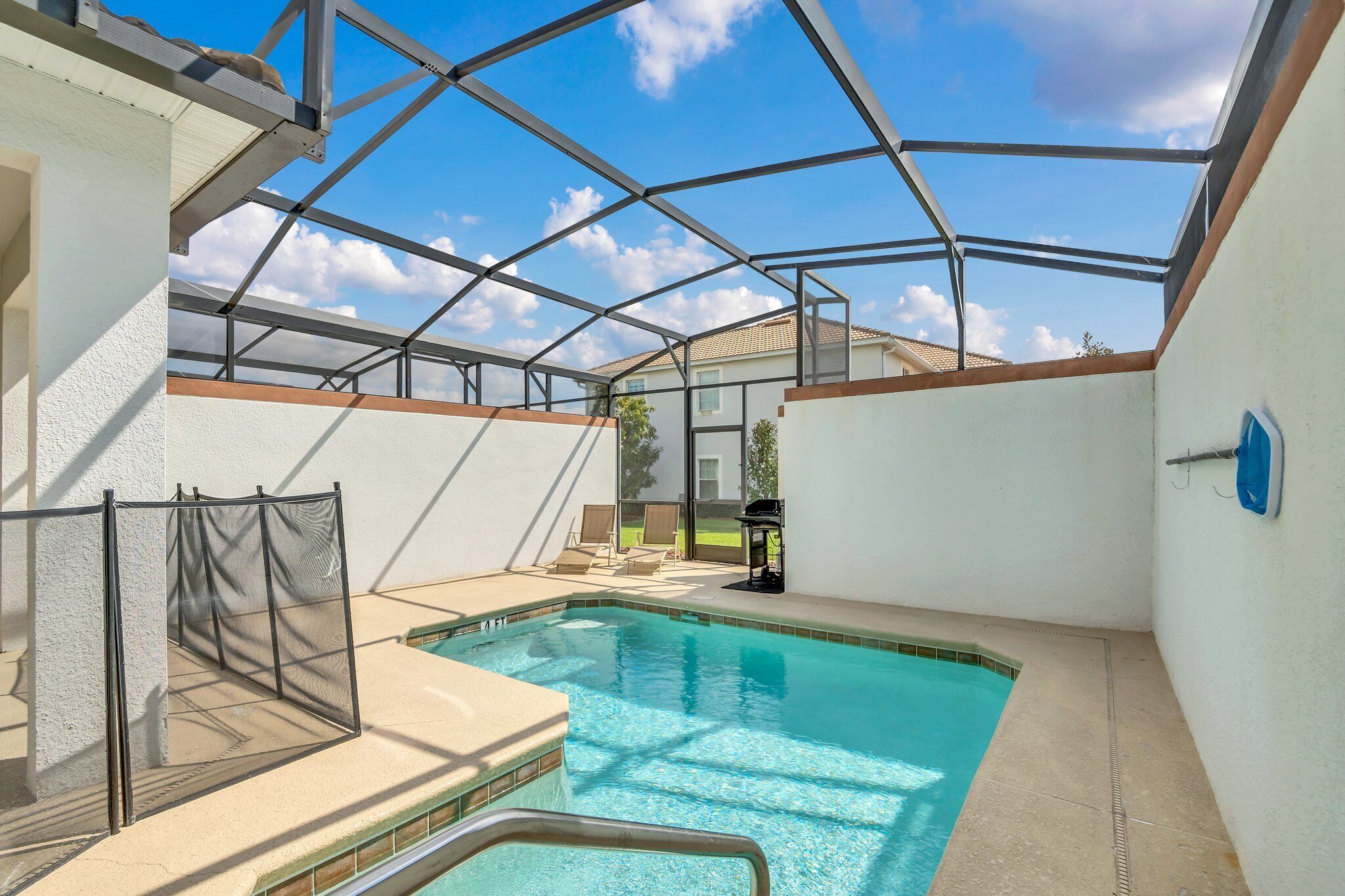 A swimming pool with a glass ceiling, surrounded by white walls and a clear blue sky.