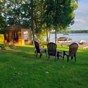 A small wooden cabin with a door and window, surrounded by a grassy area with two Adirondack chairs. - Stunning Lakehouse with all the luxuries of home (Dunsford)