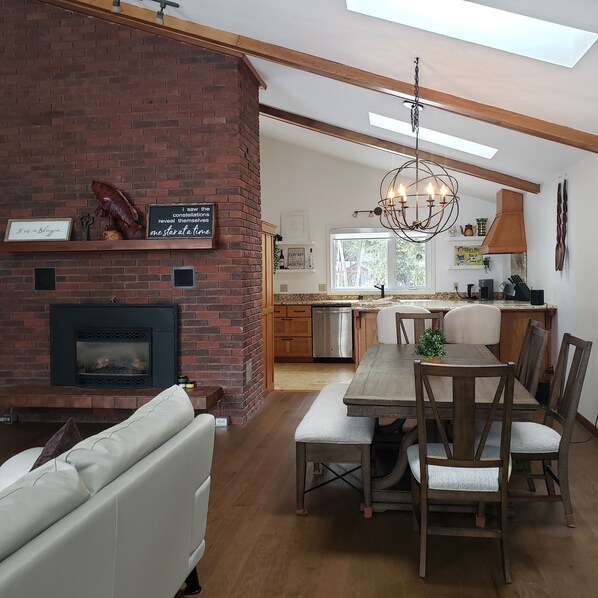 A modern kitchen with a brick fireplace, wooden dining table, and a chandelier. - Stunning Lakehouse with all the luxuries of home (Dunsford)