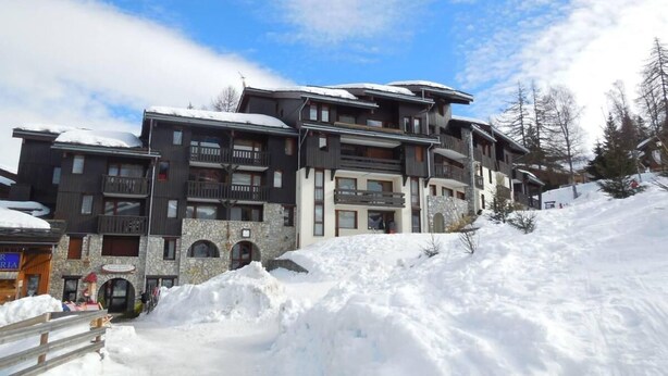 Un hotel de varios pisos con balcones y fachada de piedra, rodeado de nieve.