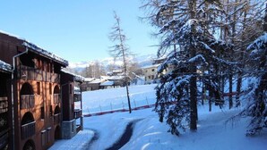 Camino cubierto de nieve que conduce a un edificio con fachada de madera y ventanas arqueadas.