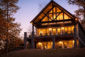 A multi-story log cabin with large windows and stone pillars.