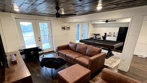 A spacious living area with a brown leather sofa, a pool table, and a wooden ceiling.