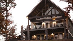 A multi-story building with a stone facade, large windows, and a balcony with outdoor seating.
