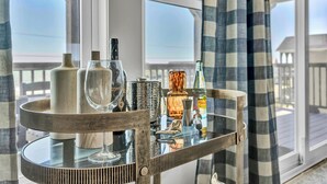 Un tavolo in vetro con diverse bottiglie e un bicchiere da vino su un balcone che si affaccia sul mare.