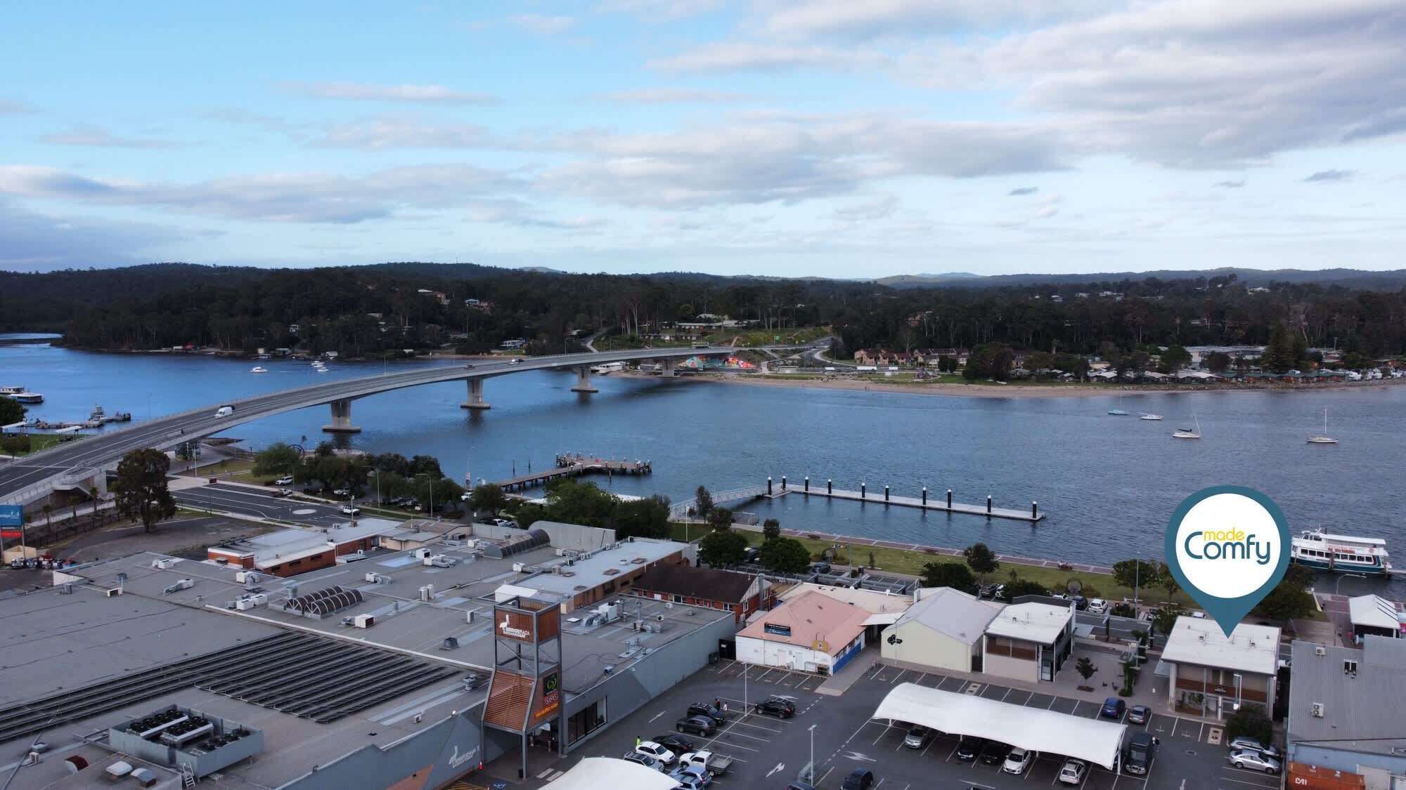A coastal town with a bridge over water, a marina, and various buildings including a hotel.