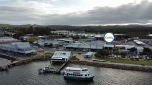 Eine Stadt am Flussufer mit einem Anleger, einem Boot und einer Mischung aus Geschäfts- und Wohngebäuden.