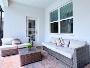 A patio with two sofas, a wicker coffee table, and a door with a window.