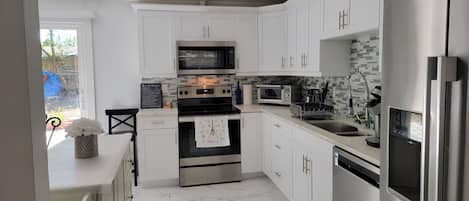 A modern kitchen with white cabinets, stainless steel appliances, and a tiled backsplash.