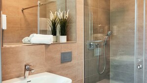 A modern bathroom with a glass-enclosed shower, a white sink, and a mirror above the sink.
