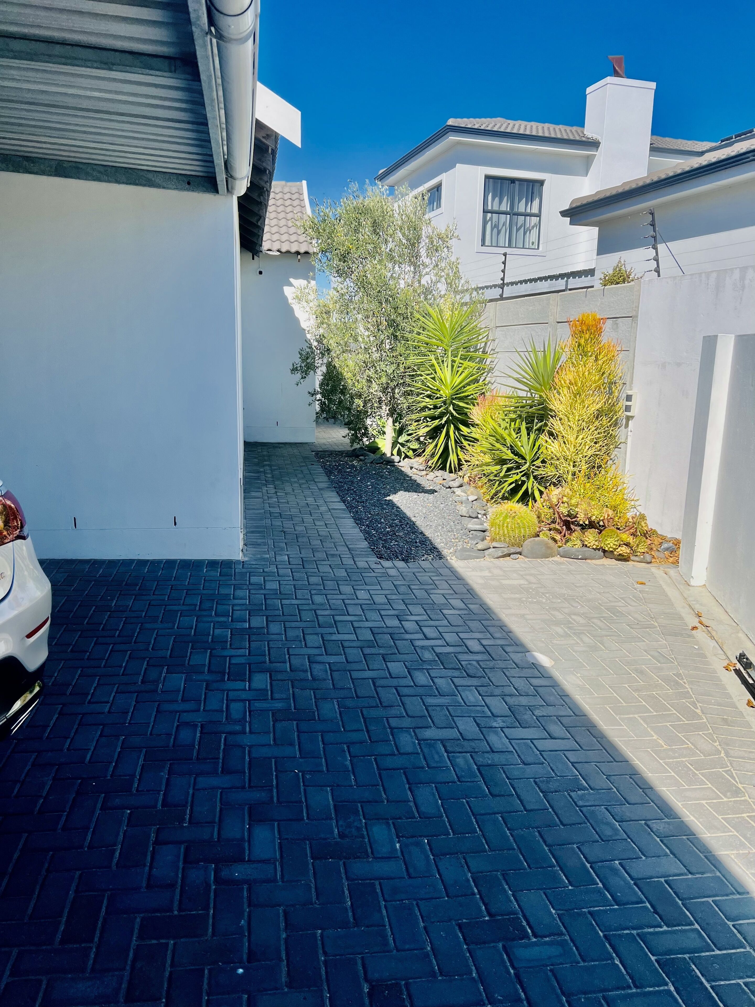 A paved driveway leading to a white building with a tiled roof.