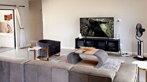 Uma sala de estar moderna com um sofá seccional, uma TV de tela plana e um design minimalista.