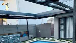 Piscina com parede de pedra e grama sintética ao redor.