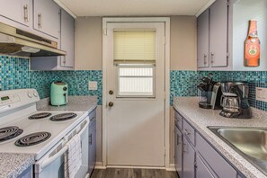 A kitchen with a white stove, a coffee maker, and a sink.