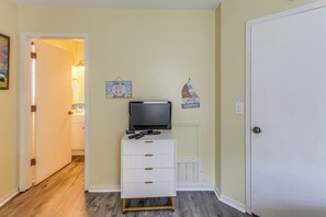 A hallway with a television on a stand, a white cabinet, and two wall decorations.