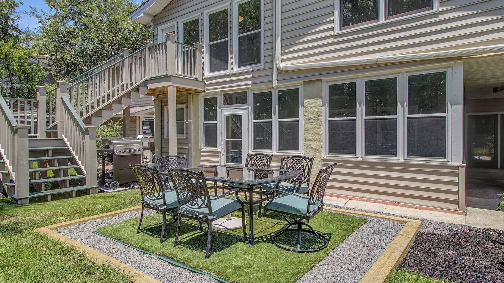 A two-story house with a covered patio, a staircase, and a barbecue grill.