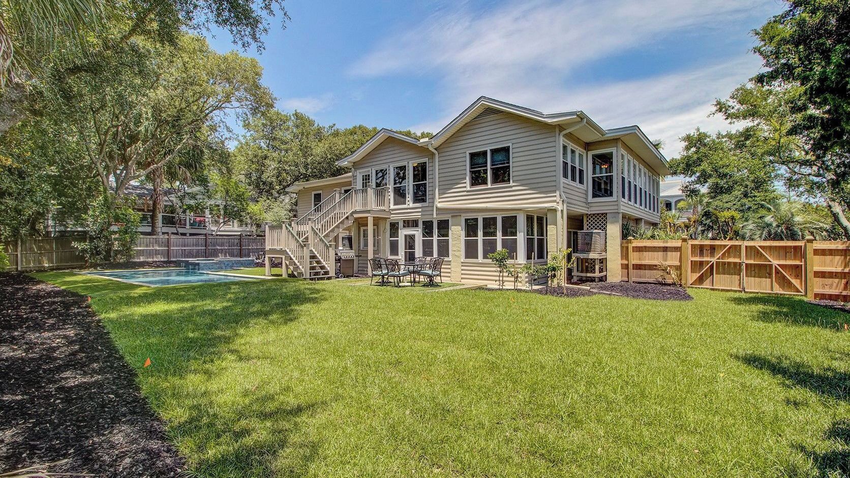 A two-story house with a large backyard, a wooden deck, and a swimming pool.