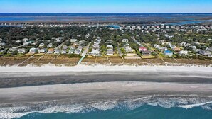 An aerial view of a coastal residential area with houses along the beachfront, a sandy beach, and a view of the ocean. - 11 43rd Avenue by Avantstay Pool + Close to Beach! (Isle of Palms)
