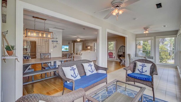 A spacious living area with wicker furniture, a dining table, and a kitchen in the background. - 11 43rd Avenue by Avantstay Pool + Close to Beach! (Isle of Palms)