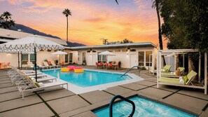 A pool area with lounge chairs, a hot tub, and a covered seating area.