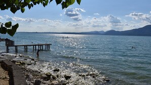 A lake with a pier extending into the water, surrounded by mountains and clear skies.